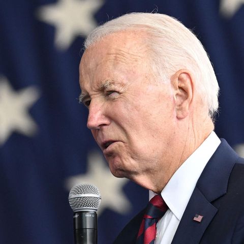 Joe Biden spricht vor einer US-Flagg in ein Mikrofon