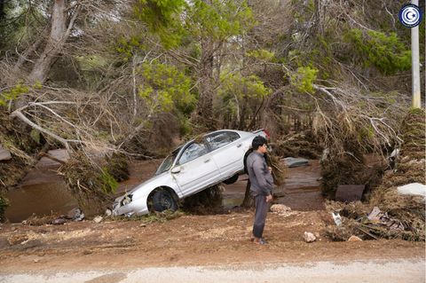 Ein Mann steht in der überfluteten Stadt Darna in Libyen neben einem weggeschwemmten Auto