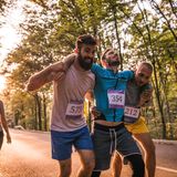 Zwei Sportler helfen einem verletzten Kontrahenten über die Ziellinie