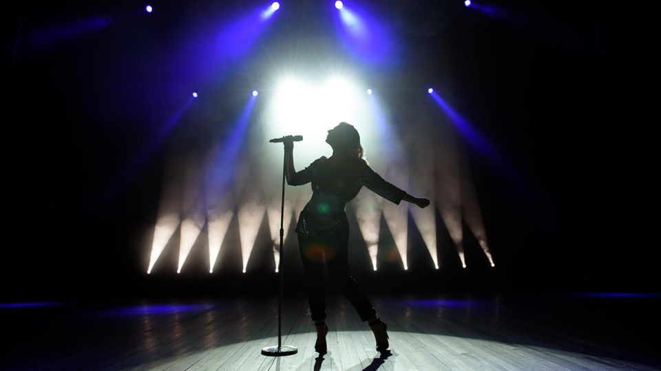 Eine Frau steht auf einer Bühne und singt ins Mikrofron.