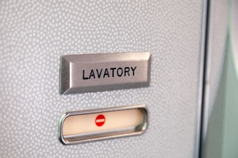 Die grau-weiß gepunktete Tür einer Flugzeugtoilette ist mit einem "Lavatory"-Schild gekennzeichnet und gerade geschlossen