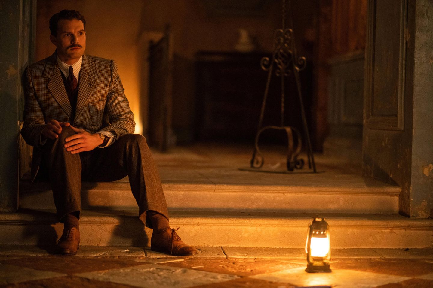 "A Haunting in Venice": Der Großteil der Handlung findet in einem beeindruckenden venezianischen Palazzo statt. Poirot und seine amerikanische Bekannte, Autorin Ariadne Oliver (Tina Fey) sind dort zu einer Séance geladen. Gastgeberin ist die Grande Dame Rowena Drake. Sie ist verzweifelt, nachdem ihre Tochter Alicia im vergangenen Jahr vom Balkon des Palazzos fiel und in den Tod stürzte. Mithilfe des Mediums Mrs. Reynolds (gespielt von Oscarpreisträgerin Michelle Yeoh) will sie Alicias Geist herbeirufen und herausfinden, was wirklich mit ihr passiert ist. Jamie Dornan spielt den Leibarzt der Drakes, der selbst geplagt ist von seiner Vergangenheit. "Venedig beschwört Vorstellungen von Fantasie und Dunkelheit herauf", sagt Dornan im Featurette zum Film über die Lagunenstadt. Der Großteil der Handlung findet in einem beeindruckenden venezianischen Palazzo statt. Poirot und seine amerikanische Bekannte, Autorin Ariadne Oliver (Tina Fey) sind dort zu einer Séance geladen. Gastgeberin ist die Grande Dame Rowena Drake. Sie ist verzweifelt, nachdem ihre Tochter Alicia im vergangenen Jahr vom Balkon des Palazzos fiel und in den Tod stürzte. Mithilfe des Mediums Mrs. Reynolds (gespielt von Oscarpreisträgerin Michelle Yeoh) will sie Alicias Geist herbeirufen und herausfinden, was wirklich mit ihr passiert ist. Jamie Dornan spielt den Leibarzt der Drakes, der selbst geplagt ist von seiner Vergangenheit. "Venedig beschwört Vorstellungen von Fantasie und Dunkelheit herauf", sagt Dornan im Featurette zum Film über die Lagunenstadt.