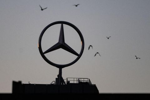 Vögel fliegen um einen Mercedes-Stern, der auf einem Gebäude im Werk Untertürkheim angebracht ist.