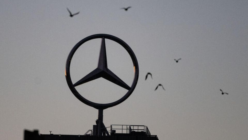 Vögel fliegen um einen Mercedes-Stern, der auf einem Gebäude im Werk Untertürkheim angebracht ist.