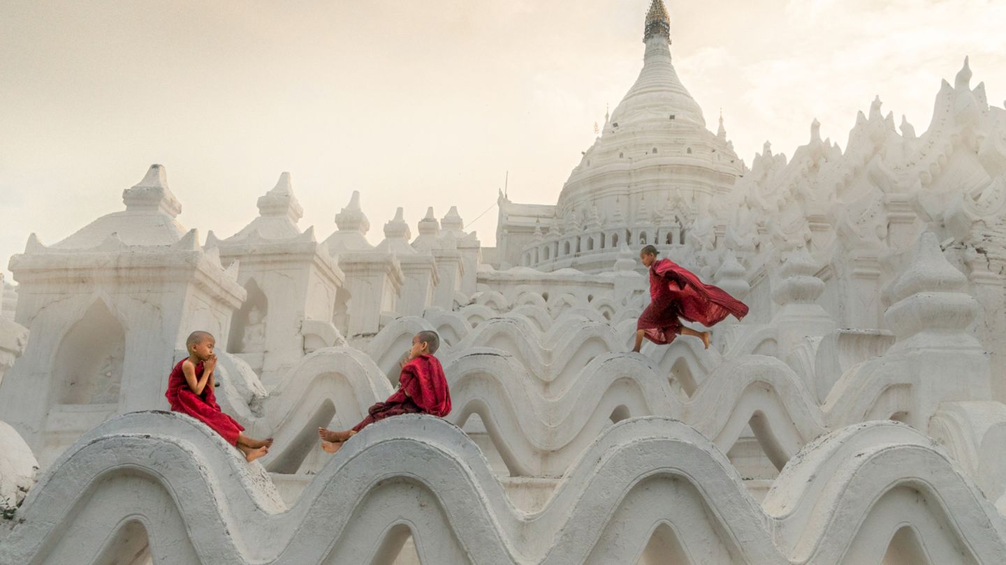 Pagoda Novice Monks  Fotograf: Chin Leong Teo; Singapur  Ort der Aufnahme: Myanmar  In Myanmar treten viele Kinder schon als kleine Jungen ins Mönchsleben ein. Sie verrichten Aufgaben in den Klöstern und lernen täglich die buddhistischen Schriften. Aber als Kinder, die sie sind, gönnen sie sich trotzdem ein wenig Spielzeit. Auf diesem Foto nimmt sich ein Mönchsnovize die Zeit, ein wenig zu rennen und zu springen, während seine Freunde sich zum Beten niederlassen