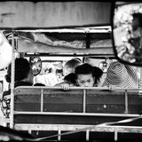 Phnom Penh  Fotograf: Gregory Herpe; Paris, Frankreich  Ort der Aufnahme: Phnom Penh, Kambodscha  Phnom Penh, Kambodscha In der kambodschanischen Hauptstadt gibt es Tausende von Tuk Tuks, und der Verkehr ist schrecklich. Touristen benutzen sie überall und auch Kambodschaner benutzen sie, wie dieser kleine Junge. Er ist mit seiner Familie unterwegs, vielleicht auf dem Weg zur Schule, und um sich die Zeit zu vertreiben, schaut er mit seinen tiefen, intensiven Augen auf die Menschen hinter ihm. Wie viele Kinder in diesem Teil Asiens hat er den dunklen Blick von Völkern, die viel gelitten haben. Im Rückspiegel fährt der Taxifahrer seine Kunden in die Innenstadt