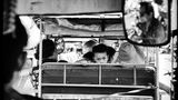 Phnom Penh  Fotograf: Gregory Herpe; Paris, Frankreich  Ort der Aufnahme: Phnom Penh, Kambodscha  Phnom Penh, Kambodscha In der kambodschanischen Hauptstadt gibt es Tausende von Tuk Tuks, und der Verkehr ist schrecklich. Touristen benutzen sie überall und auch Kambodschaner benutzen sie, wie dieser kleine Junge. Er ist mit seiner Familie unterwegs, vielleicht auf dem Weg zur Schule, und um sich die Zeit zu vertreiben, schaut er mit seinen tiefen, intensiven Augen auf die Menschen hinter ihm. Wie viele Kinder in diesem Teil Asiens hat er den dunklen Blick von Völkern, die viel gelitten haben. Im Rückspiegel fährt der Taxifahrer seine Kunden in die Innenstadt