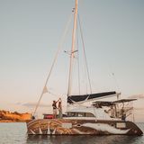 Ein Paar tanzt auf seinem Katamaran, der in einer Bucht liegt