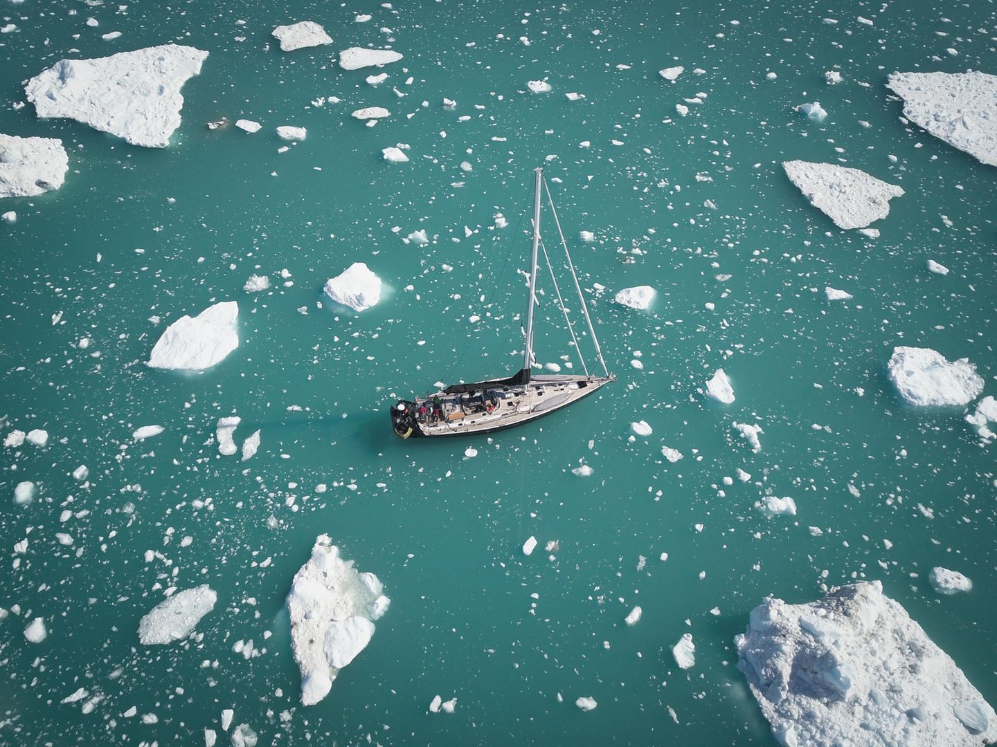 Blick von oben auf ein Schiff, das zwischen Einsschollen hindurch segelt Blick von oben auf ein Schiff, das zwischen Einsschollen hindurch segelt