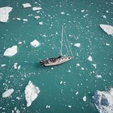 Blick von oben auf ein Schiff, das zwischen Einsschollen hindurch segelt