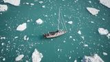 Blick von oben auf ein Schiff, das zwischen Einsschollen hindurch segelt