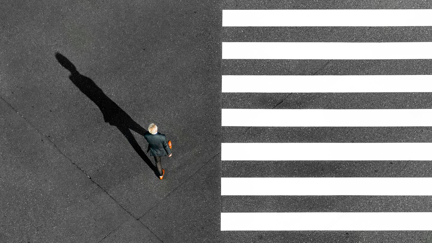 Ein Mann geht an einem Zebrastreifen entlang. Ein Mann geht an einem Zebrastreifen entlang.