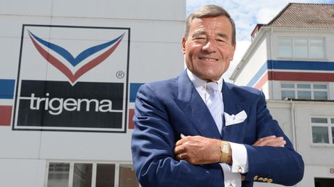  Wolfgang Grupp, Geschäftsführer des Bekleidungsunternehmens Trigema, vor einem Firmenlogo