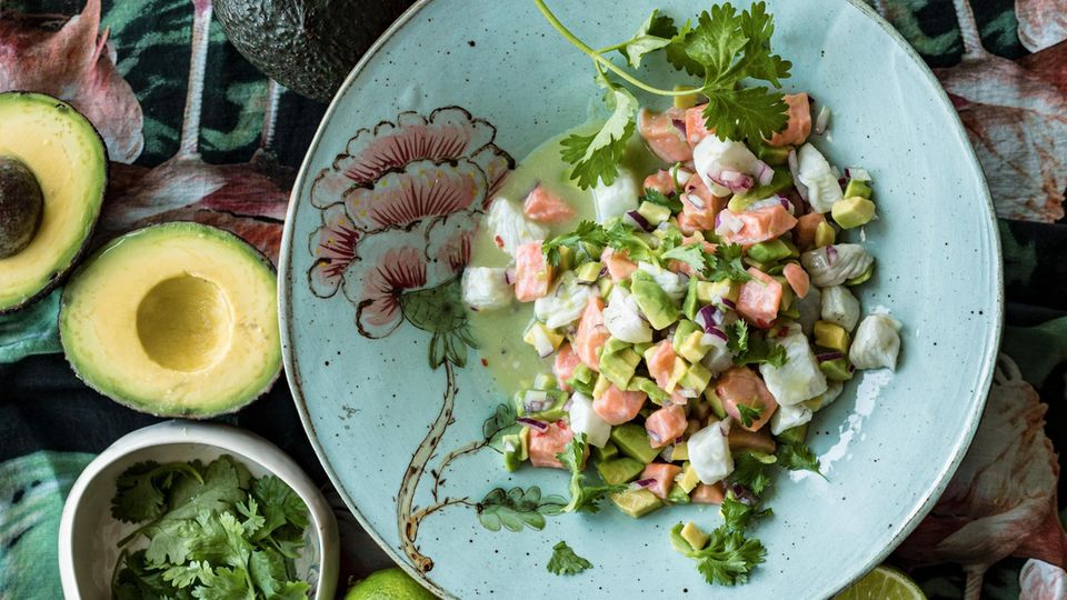 Ceviche mit Lachs peruanische Art auf einem Teller mit Avocados und Limetten daneben