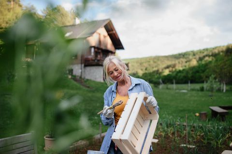 Eine ältere Frau streicht eine Holzkiste