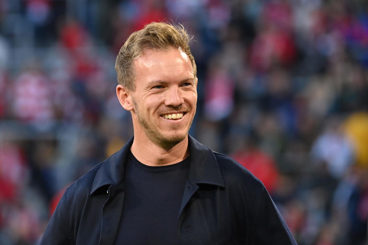 Julian Nagelsmann, schwarzes T-Shirt, schwarzer Mantel, lacht am Spielfeldrand Julian Nagelsmann, schwarzes T-Shirt, schwarzer Mantel, lacht am Spielfeldrand