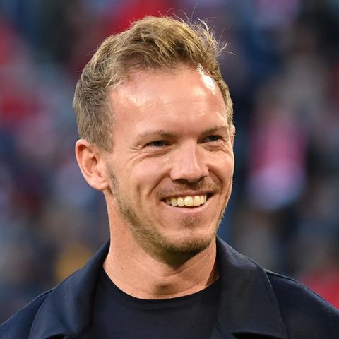 Julian Nagelsmann, schwarzes T-Shirt, schwarzer Mantel, lacht am Spielfeldrand