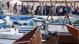 Lampedusa, Italien. Sie kommen in Strömen, um hier Schlange zu stehen: Migranten warten in einem Hafen auf der Insel Lampedusa. Wegen des Massenandrangs war das Erstaufnahmelager zuletzt zweitweise überfüllt. Frankreich hat Italien angeboten, bei der Rückführung der Menschen zu helfen. 60 Prozent der angekommenen Migranten sprechen laut dem Innenminister Französisch.