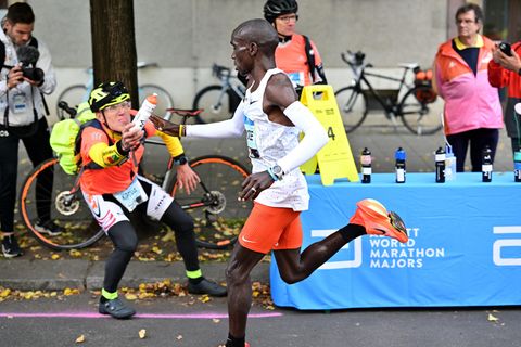Flaschen-Claus reicht einem Läufer beim Berlin-Marathon ein Getränk