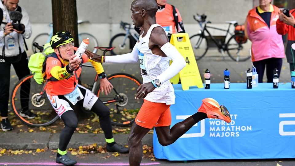 Flaschen-Claus reicht einem Läufer beim Berlin-Marathon ein Getränk