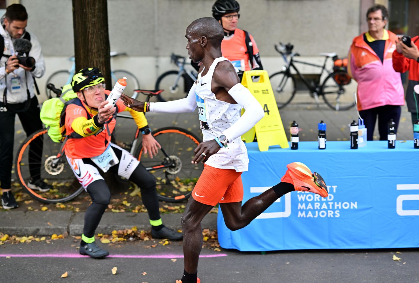 Flaschen-Claus reicht einem Läufer beim Berlin-Marathon ein Getränk