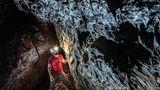 Mann mit rotem T-Shirt und brauner Hose in einer Höhle