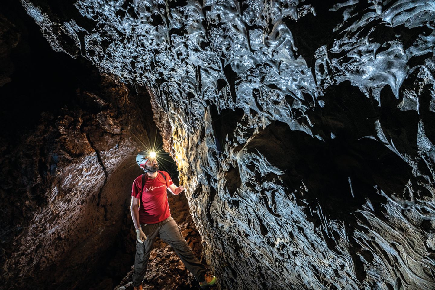Mann mit rotem T-Shirt und brauner Hose in einer Höhle