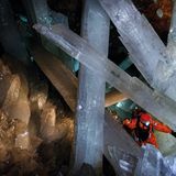 Mann mit orangerotem Anzug neben großen Kristallen