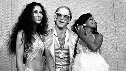 Cher und Diana Ross rahmen Elton John ein, der eine große Brille trägt