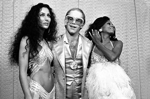 Cher und Diana Ross rahmen Elton John ein, der eine große Brille trägt