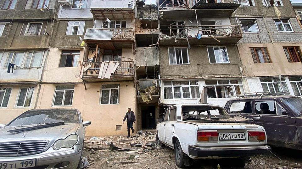 In Berg-Karabach kommt ein Mann aus dem Eingang eines zerstörten Wohnhauses