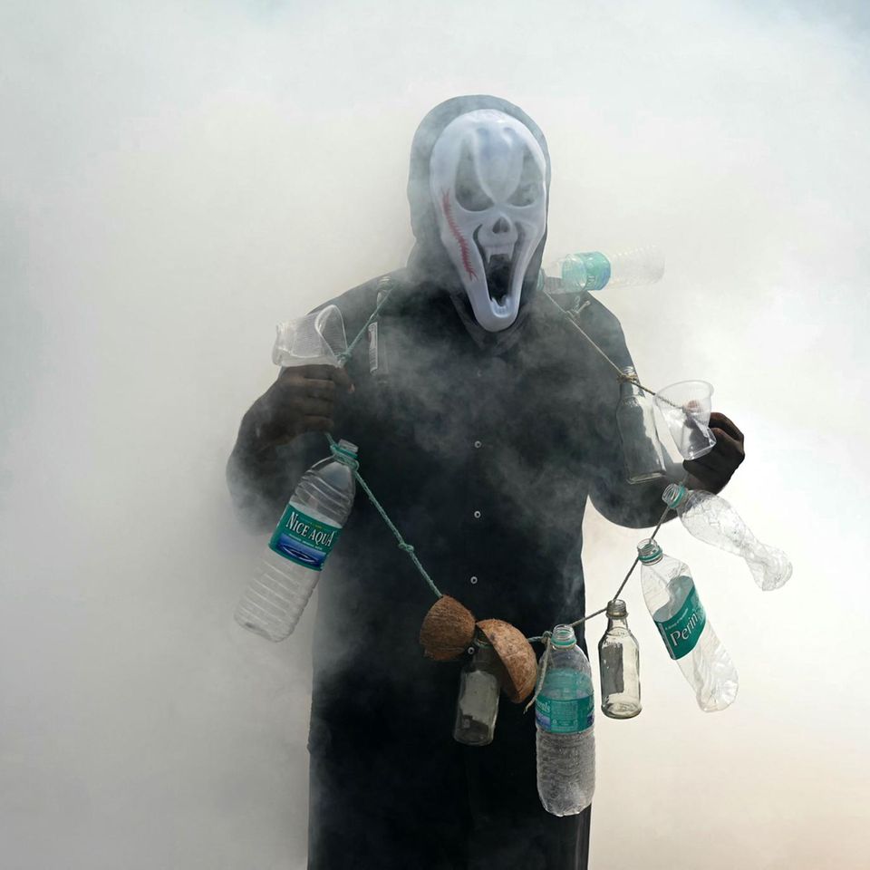 Chennai, Indien. Mit Maske, Kostüm und Flaschen macht hier jemand auf ein Problem aufmerksam: durch Moskitos übertragene Krankheiten – während Arbeiter gerade mit Ausräuchern beschäftigt sind. Fraglich, ob das Einatmen des Rauches die Gesundheit fördert.