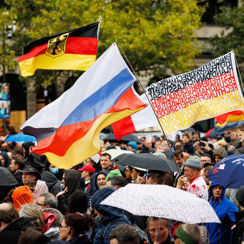 Aus einer Menschenmenge auf einer Demo in Hannover wehen deutsche Flaggen und eine russische
