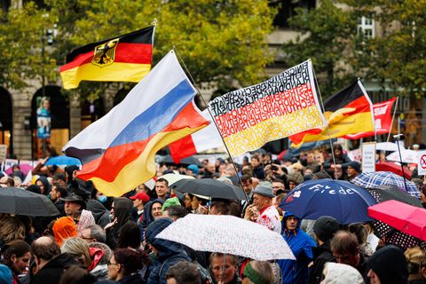 Aus einer Menschenmenge auf einer Demo in Hannover wehen deutsche Flaggen und eine russische