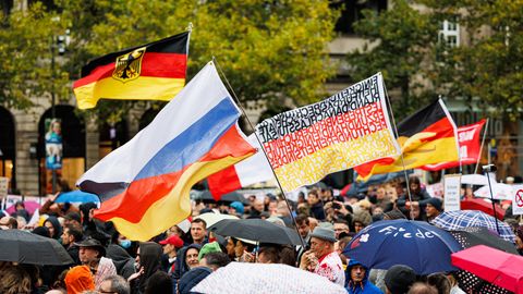 Aus einer Menschenmenge auf einer Demo in Hannover wehen deutsche Flaggen und eine russische