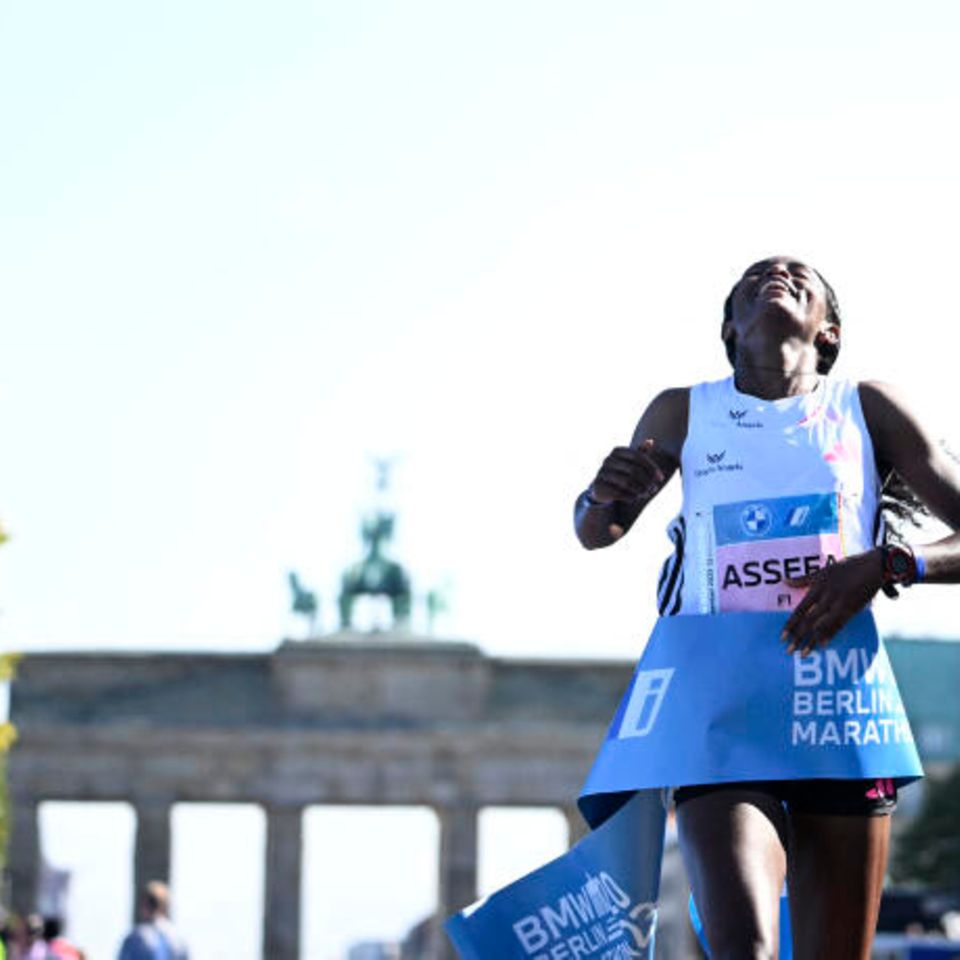 Berlin, Deutschland. Kurz hinter dem Brandenburger Tor bekreuzigt sich Tigst Assefa erst und sinkt dann auf die Knie. Sie hat es geschafft. Unter strahlend blauem Himmel überquert die 29-jährige Äthiopierin als erste Frau die Ziellinie beim Hauptstadt-Marathon. In 2:11:53 Stunden bleibt sie mehr als zwei Minuten unter der bisherigen Bestmarke.