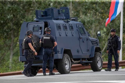 Drei Polizisten aus dem Kosovo sichern eine Straße, die zum belagerten Kloster führt