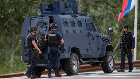 Drei Polizisten aus dem Kosovo sichern eine Straße, die zum belagerten Kloster führt