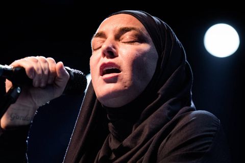 Sinéad O'Connor singt mit geschlossenen Augen auf einer Bühne