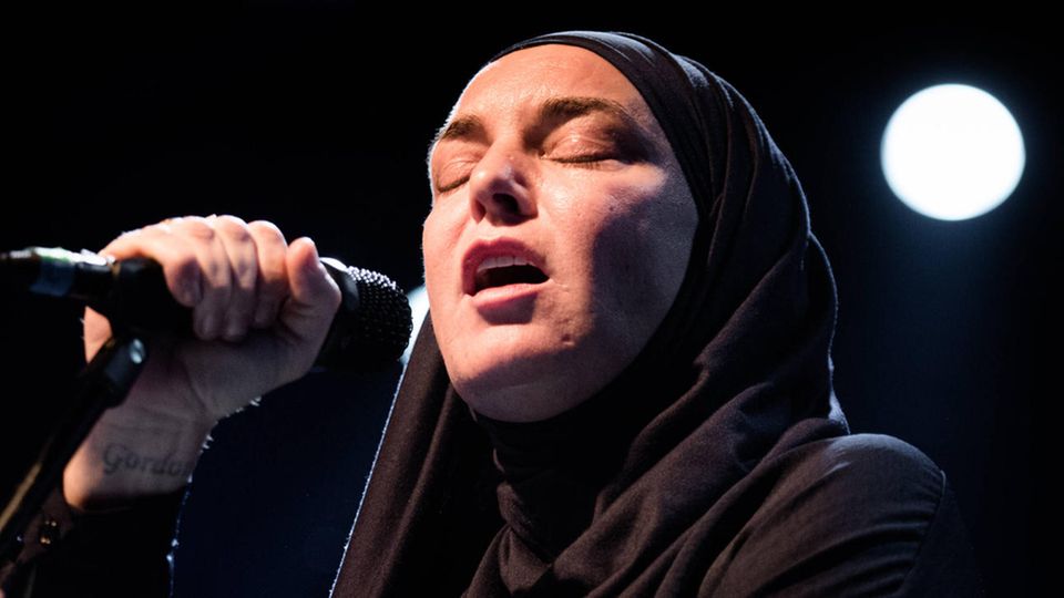 Sinéad O'Connor singt mit geschlossenen Augen auf einer Bühne