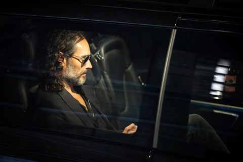 Russell Brand sitzt mit Sonnenbrille in einem dunklen Auto