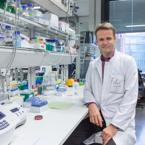 Harald Prüß forscht zu Long Covid. Hier sitzt er im weißen Arztkittel in einem Labor