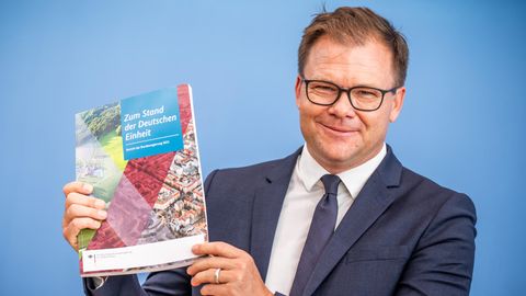 Carsten Schneider zeigt den Bericht zum Stand der Deutschen Einheiheit