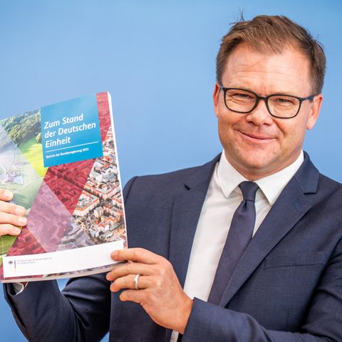 Carsten Schneider zeigt den Bericht zum Stand der Deutschen Einheiheit