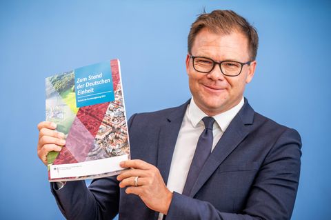 Carsten Schneider zeigt den Bericht zum Stand der Deutschen Einheiheit