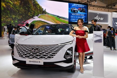 Eine Frau steht neben dem Omoda 5 des China-Herstellers Chery