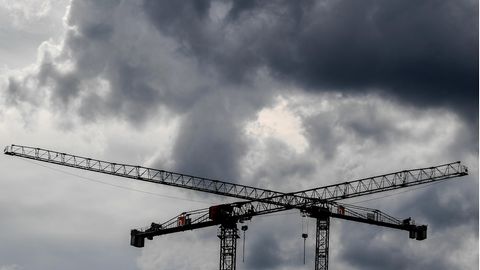 Dunkle Wolken stehen über zwei Baukränen: Symbolbild Rezession Deutschland