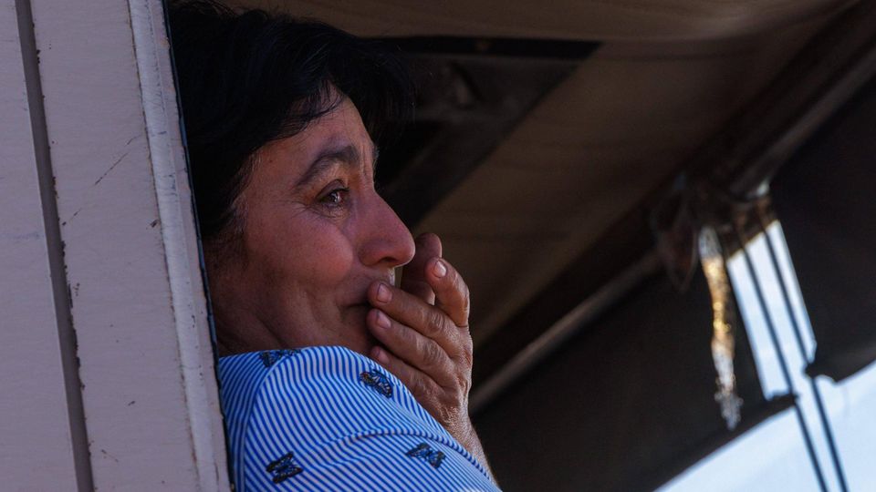 Mittelalte Frau sitzt in einem LKW und hält sich tränenden Augen die Hand vor den Mund.