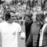 Overaths Karriere ist geprägt durch die legendäre Konkurrenz mit dem anderen großen deutschen Spielmacher der Zeit, Günter Netzer. So kommt es zu einem Kuriosum: Bei den WMs 1970 und 1974 ist Overath Spielmacher der Nationalelf, 1972 (aus dem Jahr stammt das Bild und zeigt die beiden in ihren jeweiligen Vereinstrikots) gibt der Bundestrainer Netzer den Vorzug. Weil sich Overath vor dem Turnier zudem verletzt, entstehen keine großen Diskussionen. Und es funktioniert. Netzer führt die Nationalmannschaft zum Titel. Bemerkenswert ist, dass sich die beiden Stars privat gut verstanden und bis heute gute Freunde sind.