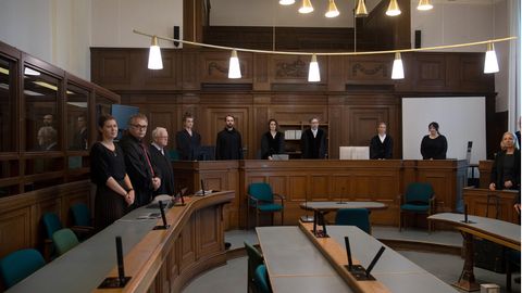 Foto in einen Gerichtssaal mit stehen Richtern und weiteren Personen
